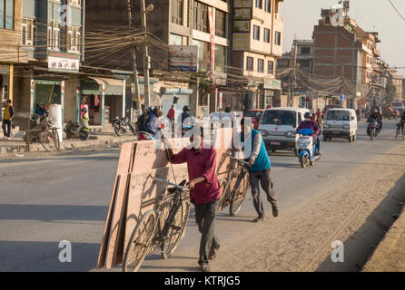 Men using bicycles to transport sheets of plywood timber in Kathmandu, Nepal Stock Photo