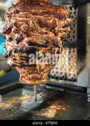 Close up of vertical spit in front of grilling heat source for tacos al pastor - a Mexican street food specialty. Stock Photo