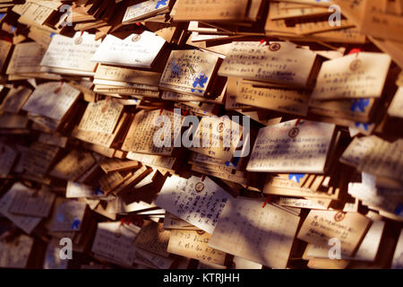 Artistic photo of Ema, Japanese wooden votive plates with written prayers and wishes, hanging at a Shinto shrine in Kyoto, Japan for Kami spirits to r Stock Photo