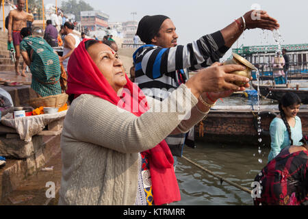 Pilgrims pray on the ghats beside the River Ganges in Varanasi Stock Photo