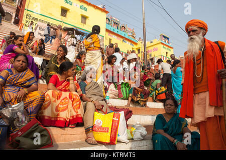 Pilgrims and a saddhu on Kesar Ghat beside the River Ganges in Varanasi Stock Photo