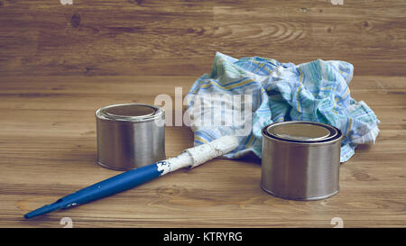 Black and white paint cans with brush and dirty rag on wooden background Stock Photo