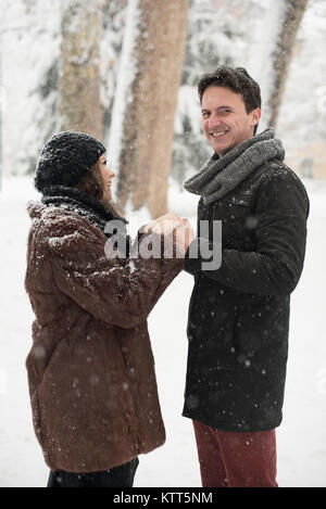 Couple standing in park holding hands in the snow Stock Photo