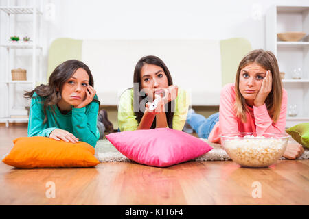 Three friends are watching movie on TV. Stock Photo