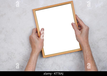The old man tries to hang a wooden frame with a photograph on the wall. Concept studio shot. Picture isolated on white with patch. Stock Photo