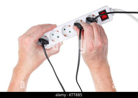 Old elderly man tries to insert a wire with an electrical plug into the main extension cord with sockets. Isolated on white top view studio shot Stock Photo
