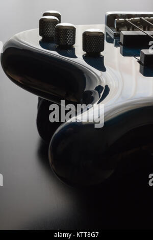 A blue five string bass guitar is strategically positioned in the frame with a black wooden background. This is a darker image which emphasizes the sl Stock Photo