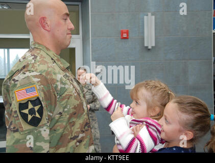 Maya Starr holds up her little sister Gwyn as they put new rank on their father, Chief Warrant Officer 2 Matthew Starr during his promotion ceremony on March 31, 2017 at New York National Guard headquarters in Latham, N.Y. Starr works in the New York National Guard federal personnel office. ( U.S. Army National Guard photo by Eric Durr) Stock Photo