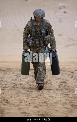 New Jersey Army National Guard Specialist Joseph Garback carries a pair of water containers from one end of the firing range to another during a training scenario at the Region One Best Warrior Competition at Joint Base McGuire-Dix-Lakenhurst on 26 April 2017.  Fourteen Soldiers are competing in the three-day event, April 25-27, 2017, which features timed events, including urban warfare simulations, a 12-mile ruck march, land navigation, and the Army Physical Fitness Test. The two winners will go on to compete in the 2017 Army National Guard Best Warrior Competition to be named the Army Guard' Stock Photo