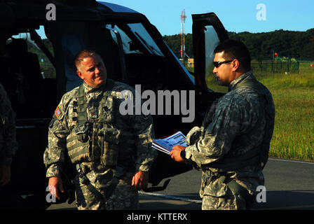 Army Chief Warrant Officer 3 Matt Quackenbush, right, provides an aircrew briefing to Maj. Paul Bailie as aircrews of the New York Army National Guard’s Company A, 3rd Battalion, 142nd Aviation Regiment prepare for takeoff and deployment from Albany International Airport in Latham, N.Y. to Florida in support of the Guard response to Hurricane Irma September 11, 2017.  Ten UH-60 Blackhawk helicopters and 55 aircrew members and maintainers deployed from three flight facilities across the state to support the Florida Army National Guard. U.S. National Guard photos by Col. Richard Goldenberg. Stock Photo