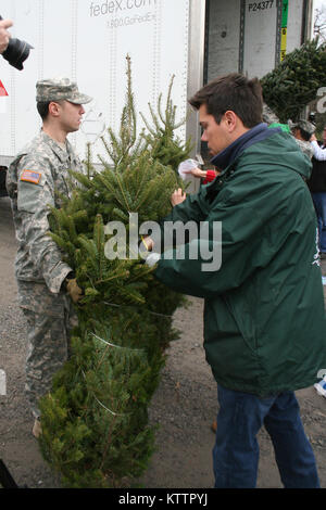 CHARLETON, N.Y. -- New York Army National Guard Spc. Raymond Gonzalez holds a Christmas Tree as Garth Ellms from Ellms Tree Farms places holiday wishes on the tree for delivery Nov. 28.  Gonzalez, and another six Soldiers from the 42nd Infantry Division Special Troops Battalion volunteered to assist in the annual &quot;Trees for Troops&quot; loading of about 115 donated trees bound for military installations and families around the country and the globe.  U.S. Army photo by Lt. Col. Richard Goldenberg, NY Army National Guard (RELEASED) Stock Photo