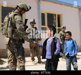 Sgt. 1st Class Grant Burtch, platoon sergeant for the personal security detail, assigned to Headquarters Company, 37th Infantry Brigade Combat Team, shakes hands with a student as he leaves the Aliabad School as Sgt. John Dewey, team leader for the PSD, and Spc. Heather De Le Vega, medic for the PSD, look on, near Mazar-e-Sharif, Balkh Province, Afghanistan, April 3, 2012. A new school is being built for the students as one of the 37th's commander's emergency relief program projects. The 37th IBCT is deployed to Afghanistan in support of Operation Enduring Freedom. (37th IBCT photo by Sgt. Kim Stock Photo