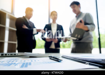 business document in touchpad lying on the desk, office workers discussting meeting in the background Stock Photo
