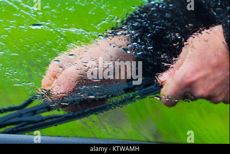 the man in the rain repairs a window wiper by car Stock Photo