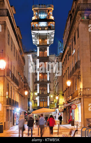People in nocturnal downtown Lisbon with illuminated Santa Justa elevator in the center