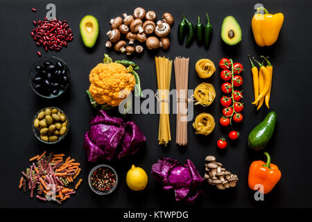 Different colorful Fresh raw ingredients for healthy vegetarian cooking on a black background. Flat lay, top view. Stock Photo