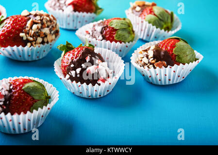 ripe strawberries dipped in  chocolate with nuts and caramel on blue background Stock Photo