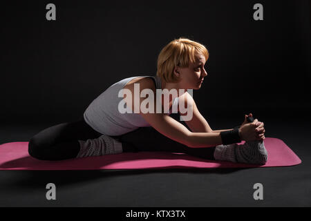 Young woman practicing yoga, Upavistha Konasana / Wide Angle Seated Forward Bend pose Stock Photo