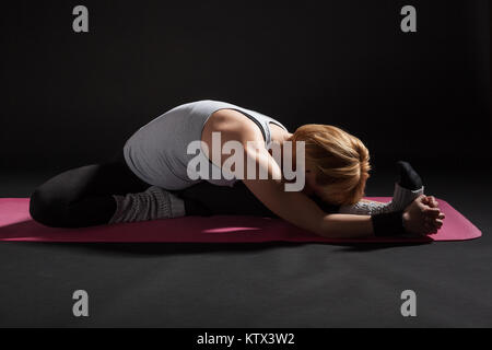 Young woman practicing yoga, Upavistha Konasana / Wide Angle Seated Forward Bend pose Stock Photo