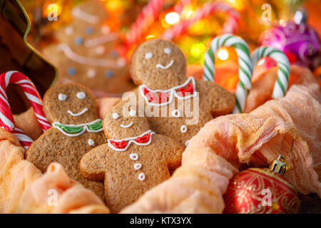 Three ginger Christmas cookies with lolipop on the background of the included garland in the festive atmosphere of the new year Stock Photo