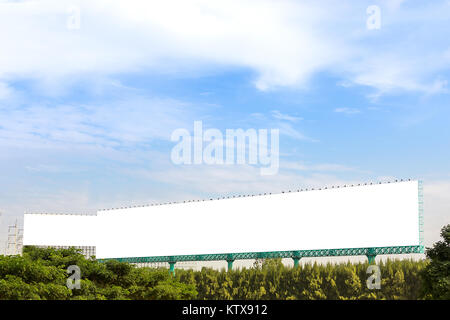 big and long billboard above the tree near highway with clear sky Stock Photo