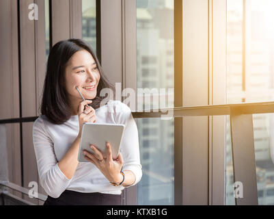 smile business woman is thinking with tablet in modern office Stock Photo