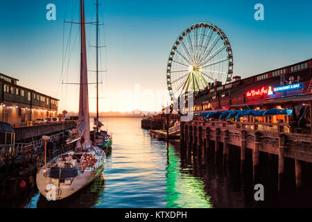 Sunset over mountains with Seattle Great Wheel on Pier 57 in the foreground. Seattle, Washington State, United States of America, North America Stock Photo