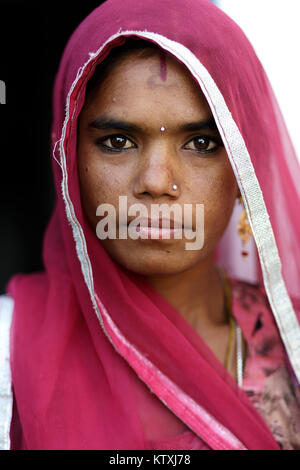Portrait of young indian woman wearing sari and a veil over her hair in her home, village near Pushkar, Rajasthan, India. Stock Photo
