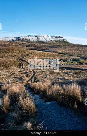 The moon rises over a snow-capped Pen-y-ghent hill seen from the Three-Peaks footpath to the west. Near Horton-in-Ribblesdale, North Yorkshire Stock Photo