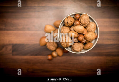 A bowl of healthy mixed whole nuts in their shells including walnuts, hazelnuts, almonds and pecans shot from above Stock Photo