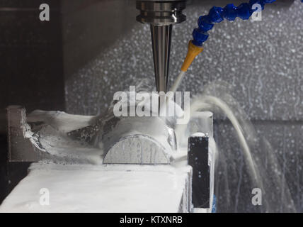 CNC machining Center is cutting part with white coolant ; selective focus Stock Photo