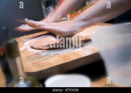 Rolling out pizza base on wooden board Stock Photo