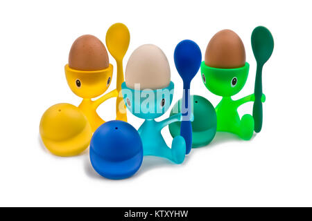 Three boiled eggs in colourful children's character egg cups, cutout on white background Stock Photo
