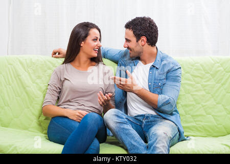 Happy couple sitting on sofa at their home. Stock Photo