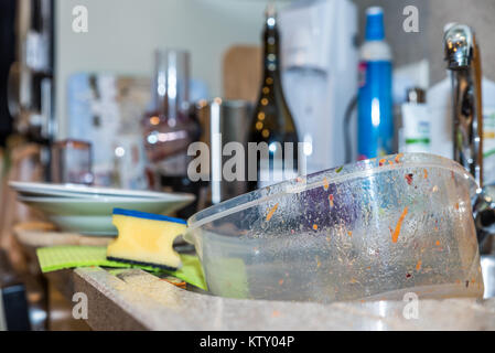Empty used dirty plastic food container box in kitchen washing sink. Stock Photo