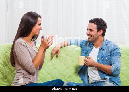 Happy couple sitting on sofa at their home and drinking tea. Stock Photo