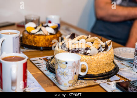 Tea cups mugs with two dessert cake tarts on wooden table at home. Stock Photo