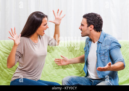 Young couple is arguing at home. They are yelling at each other. Stock Photo