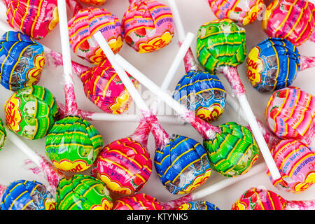 Variety of multi coloured lolly pops with white sticks in wrappers laying on a sweet counter Stock Photo