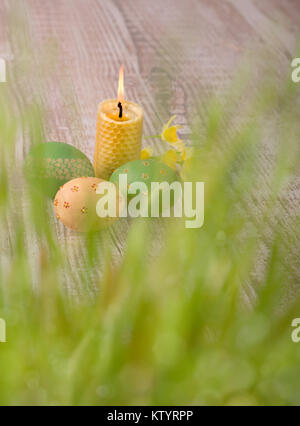 Burning beewax candle, Easter eggs behind fresh spring grass, text space Stock Photo
