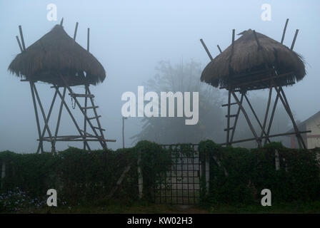 Huts of hunters and guardians near a wooden fence, bungalows on high stilts, twilight and fog. Stock Photo