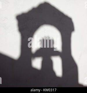 The belfry of a chapel casts a shadow in a while wall in Marinha Grande, Portugal. The bell will ring for church services. Stock Photo