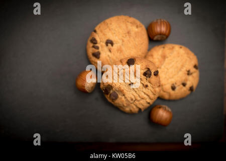 Delicious, yummy and luxurious chocolate chip and hazelnut cookies resting on a black slate background Stock Photo