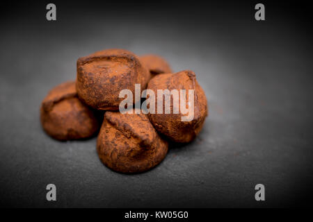 Delicious, yummy and indulgent home made luxury chocolate truffles resting on a black slate background Stock Photo