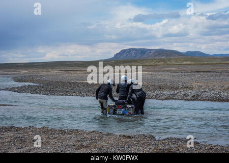 KEL-SUU, KYRGYZSTAN - AUGUST 13: Group of bikers pushing the motorbike to cross the river on off road drive in Tian Shan mountains, Kyrgyzstan. August Stock Photo