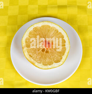 One half of a yellow grapefruit served in a white dish Stock Photo
