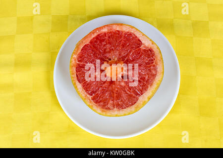 One half of a red grapefruit served in a white dish Stock Photo