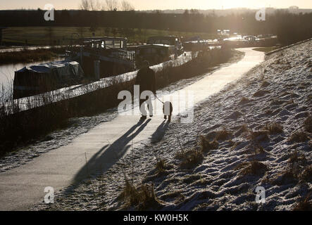 A dog walker walks along a path at the Forth and Clyde canal near the Kelpies as the cold weather continues. Stock Photo