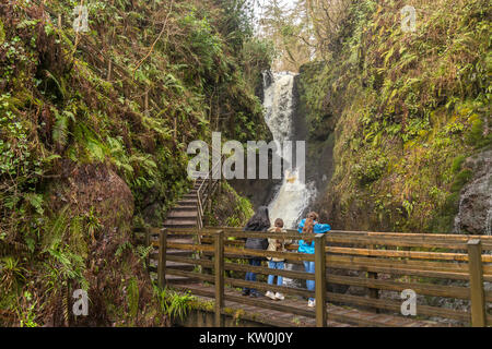Ess-na-larach waterfall in Glenariff Forest Park with a family looking at it from a wooden bridge Stock Photo