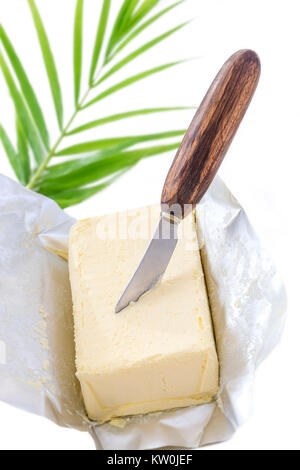 salted creamy butter in his paper packaging with knife planted in butter on white background Stock Photo